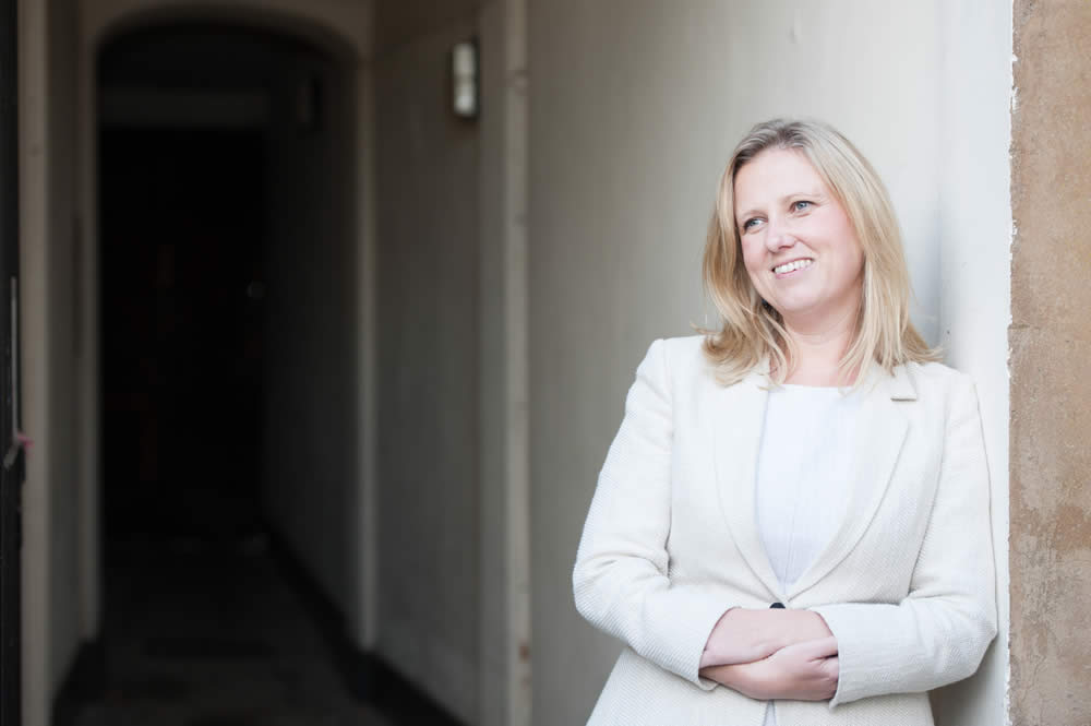 Carrie Rudge, Senior Associate & Mediator at Hedges Law, leaning against a wall